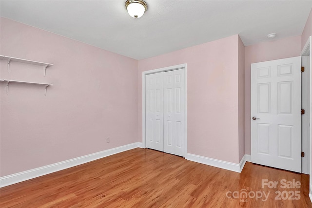 unfurnished bedroom with a closet, baseboards, and light wood finished floors