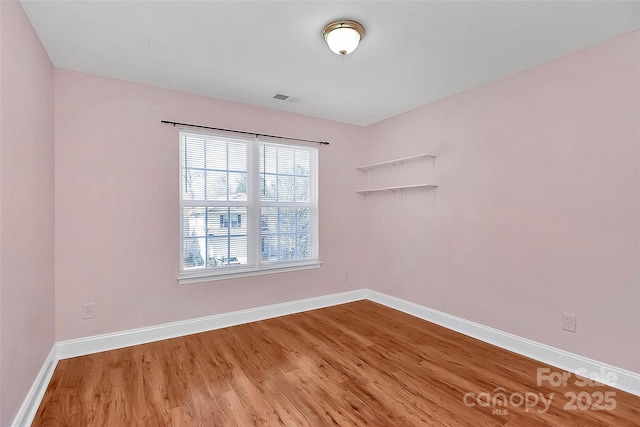 unfurnished room with visible vents, baseboards, and wood finished floors