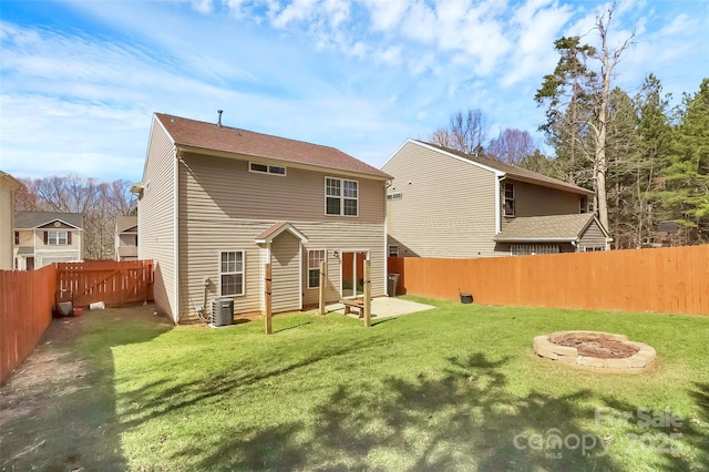 back of house featuring an outdoor fire pit, a fenced backyard, a yard, and central AC unit