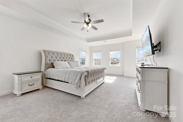 bedroom with ceiling fan, light colored carpet, baseboards, ornamental molding, and a tray ceiling