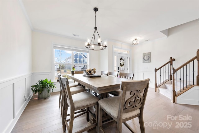 dining room with stairs, crown molding, a notable chandelier, and light wood-style floors