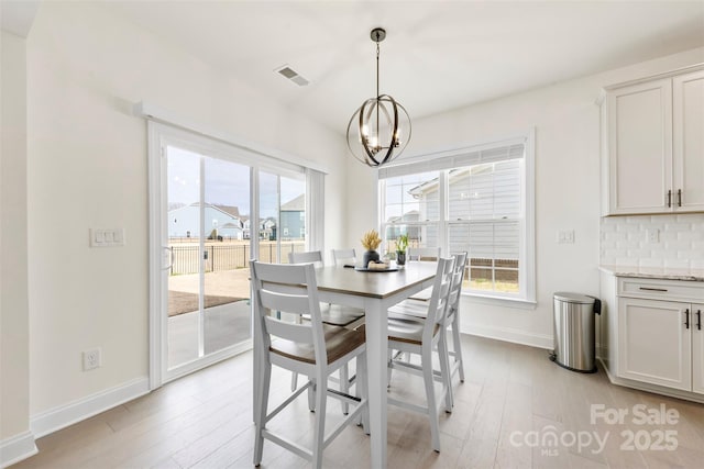 dining space with light wood-style flooring, visible vents, a chandelier, and a wealth of natural light