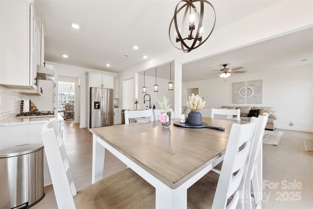 dining room featuring light wood-style floors, recessed lighting, and ceiling fan with notable chandelier