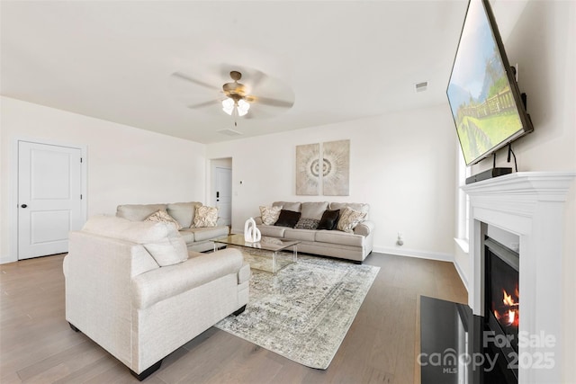 living room with visible vents, a fireplace with flush hearth, ceiling fan, wood finished floors, and baseboards