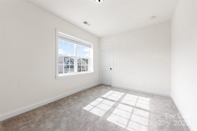 empty room with baseboards, visible vents, and light colored carpet