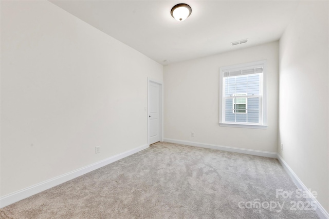 carpeted spare room featuring visible vents and baseboards