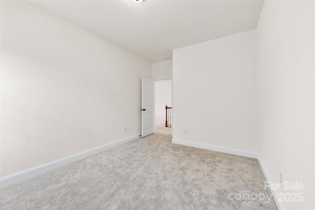 empty room featuring light carpet and baseboards