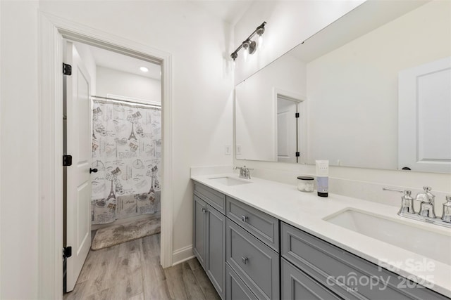 full bath featuring double vanity, wood finished floors, a shower with shower curtain, and a sink