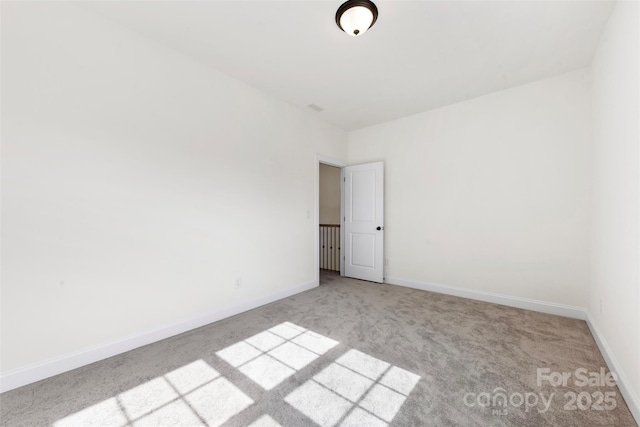 carpeted spare room featuring baseboards