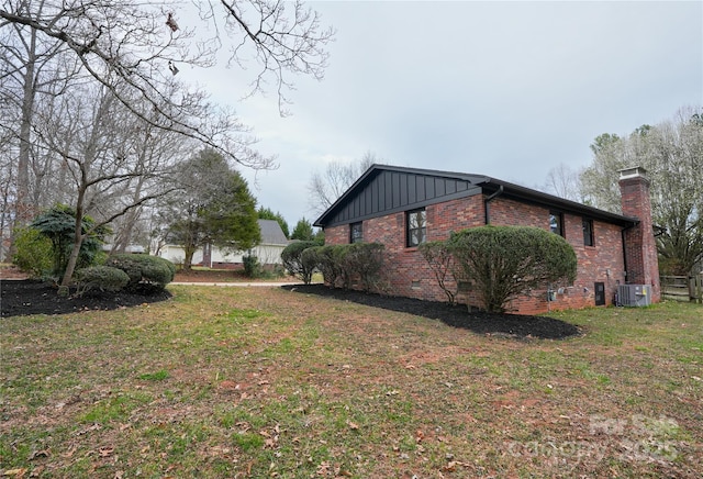 view of side of property featuring cooling unit, a yard, board and batten siding, crawl space, and brick siding