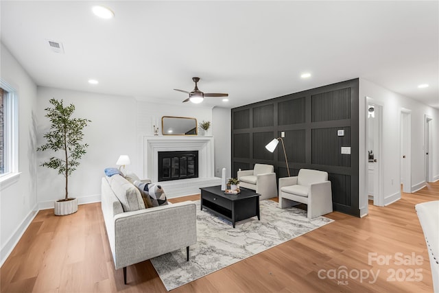 living area featuring a glass covered fireplace, recessed lighting, and wood finished floors