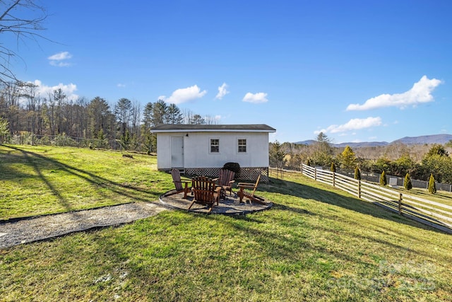 view of yard with an outbuilding, fence, a mountain view, a rural view, and a fire pit