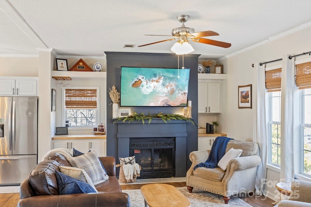 living area with plenty of natural light, visible vents, and wood finished floors