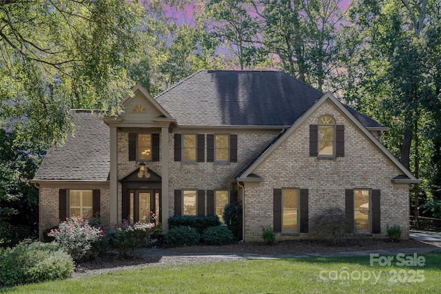 view of front of home with brick siding and roof with shingles