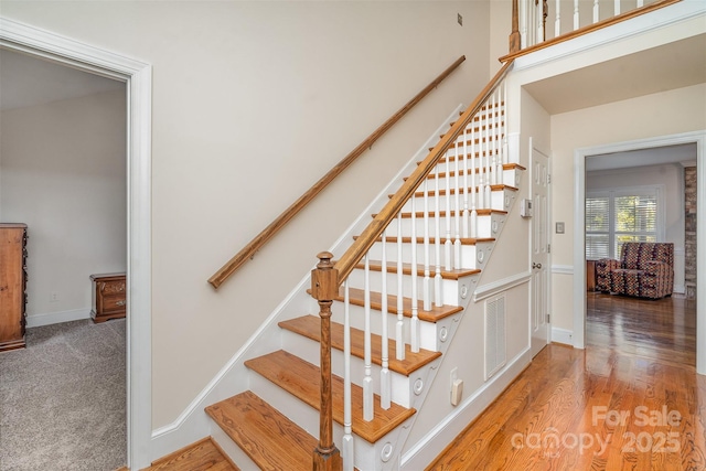 staircase with visible vents, baseboards, carpet, and wood finished floors