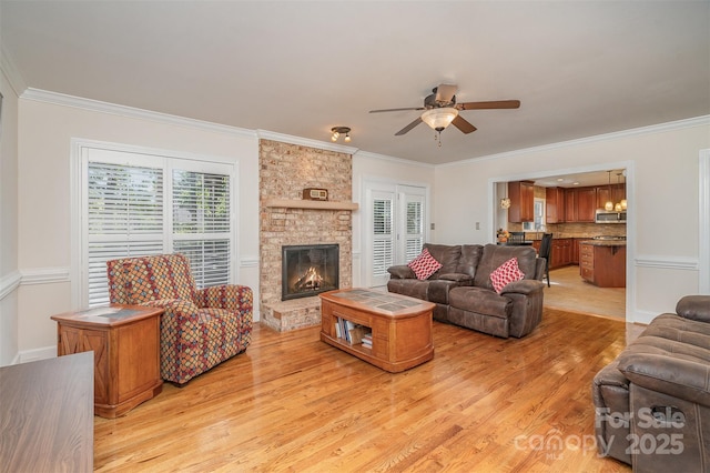 living area with a stone fireplace, crown molding, and light wood-style flooring