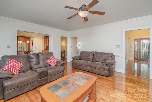 living room with ceiling fan, light wood-style floors, and ornamental molding