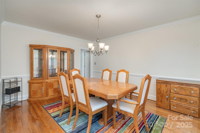 dining room with a notable chandelier, crown molding, and light wood-type flooring