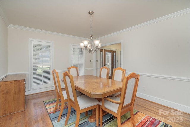 dining room featuring a notable chandelier, light wood-style flooring, crown molding, and baseboards