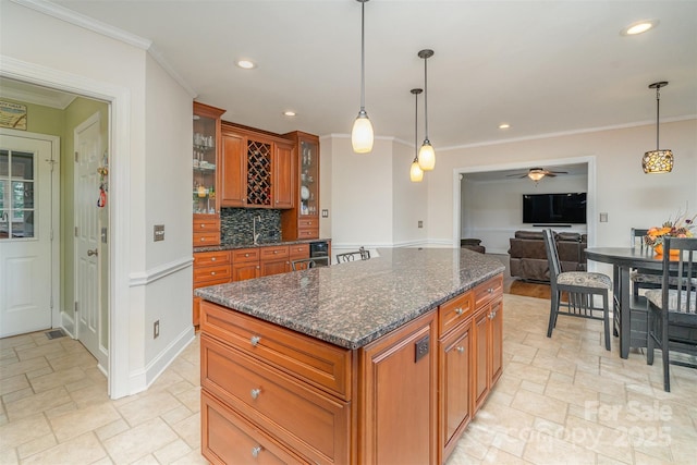 kitchen featuring brown cabinetry, stone tile flooring, decorative backsplash, glass insert cabinets, and crown molding