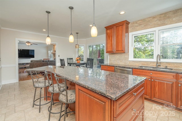 kitchen with a sink, a kitchen island, a breakfast bar area, brown cabinetry, and dishwasher