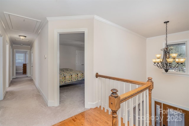 hall with crown molding, baseboards, light colored carpet, attic access, and an upstairs landing