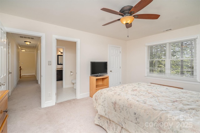 bedroom with light colored carpet, visible vents, ensuite bathroom, and baseboards