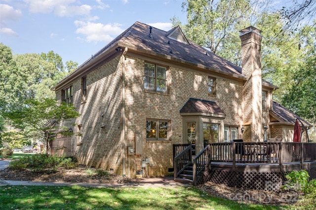 rear view of house featuring brick siding, a lawn, a chimney, and a deck