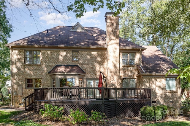 rear view of house featuring a deck, a shingled roof, crawl space, brick siding, and a chimney