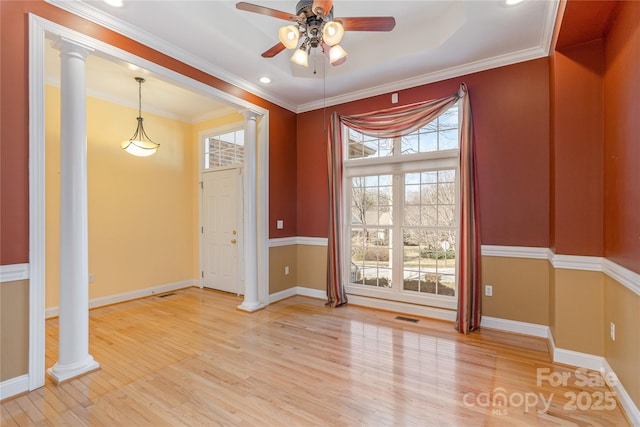 spare room featuring visible vents, light wood-style flooring, a ceiling fan, and decorative columns