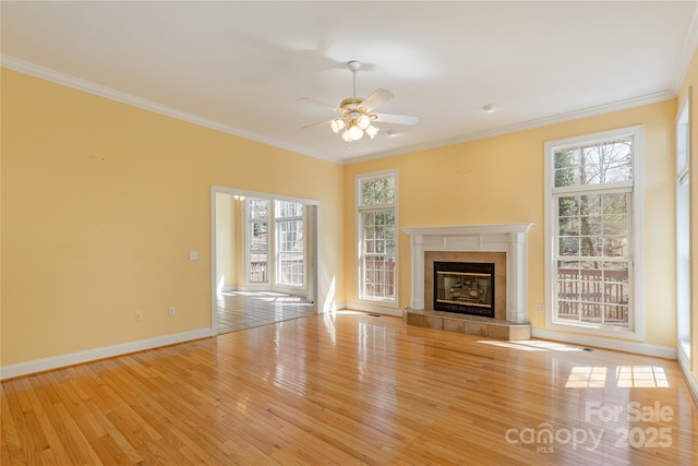 unfurnished living room with wood-type flooring, ceiling fan, crown molding, and a tile fireplace