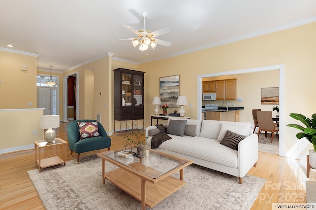 living room with baseboards, light wood-style floors, ceiling fan, and ornamental molding