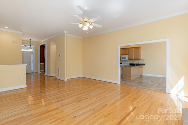 unfurnished living room featuring light wood-type flooring, baseboards, ceiling fan, and ornamental molding