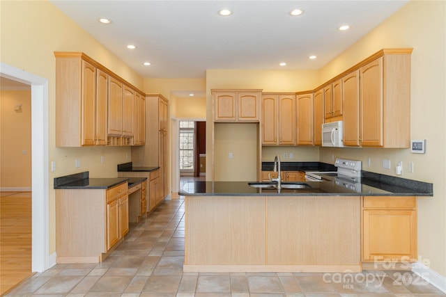 kitchen featuring light brown cabinetry, recessed lighting, a peninsula, white appliances, and a sink