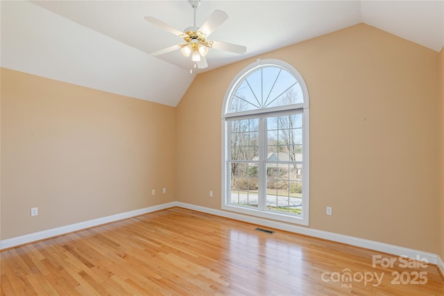 spare room featuring visible vents, baseboards, ceiling fan, light wood-type flooring, and vaulted ceiling