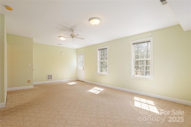 empty room with visible vents, baseboards, and ceiling fan