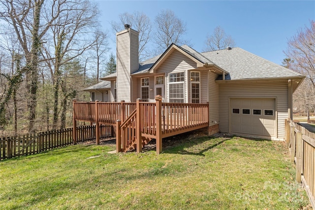 rear view of house with an attached garage, a fenced backyard, a yard, and a shingled roof