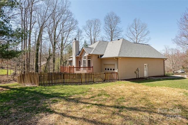 view of side of home featuring fence, a yard, a chimney, a garage, and a deck