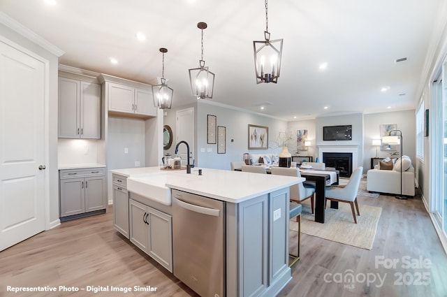 kitchen featuring gray cabinetry, a fireplace, a sink, stainless steel dishwasher, and light wood-type flooring