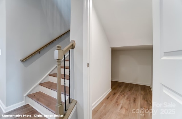 stairs with vaulted ceiling, baseboards, and wood finished floors