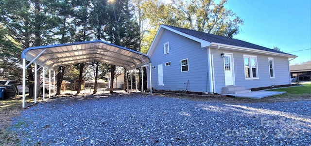 view of property exterior with a detached carport, gravel driveway, and entry steps