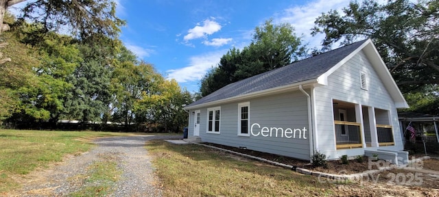 view of side of property with gravel driveway and a yard