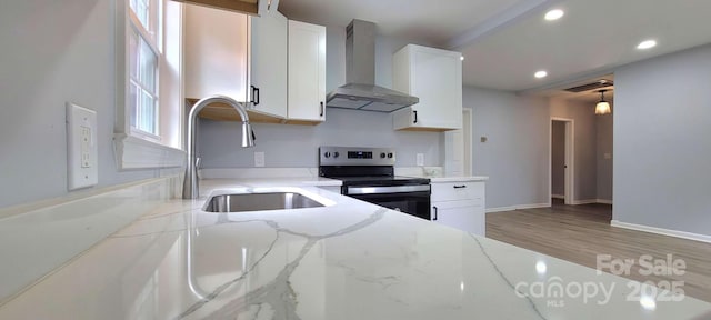 kitchen with visible vents, white cabinets, wall chimney exhaust hood, stainless steel range with electric stovetop, and a sink