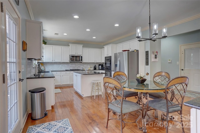 kitchen featuring dark countertops, ornamental molding, appliances with stainless steel finishes, and a sink