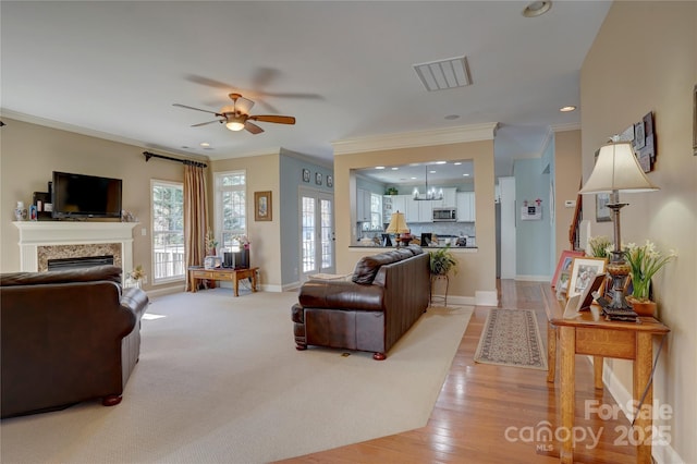 living area with baseboards, recessed lighting, a fireplace, crown molding, and ceiling fan with notable chandelier