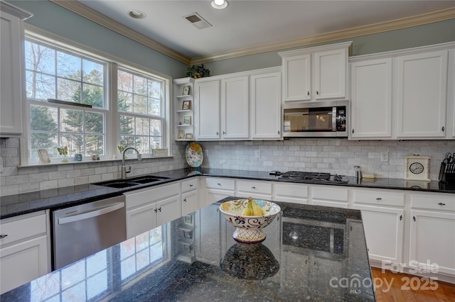 kitchen featuring visible vents, a sink, decorative backsplash, stainless steel appliances, and crown molding