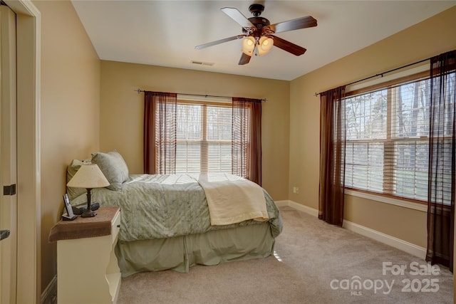 bedroom with ceiling fan, light colored carpet, visible vents, and baseboards