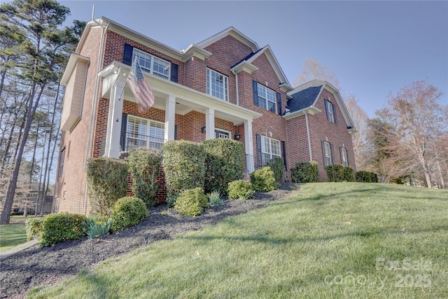 view of side of property featuring brick siding and a yard