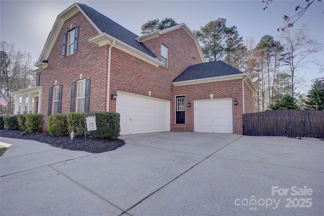 view of home's exterior featuring an attached garage, fence, brick siding, and driveway