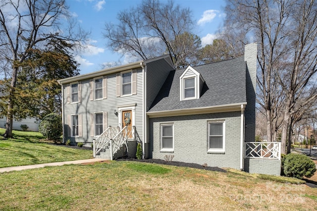 colonial inspired home with brick siding, a chimney, a front lawn, and a shingled roof